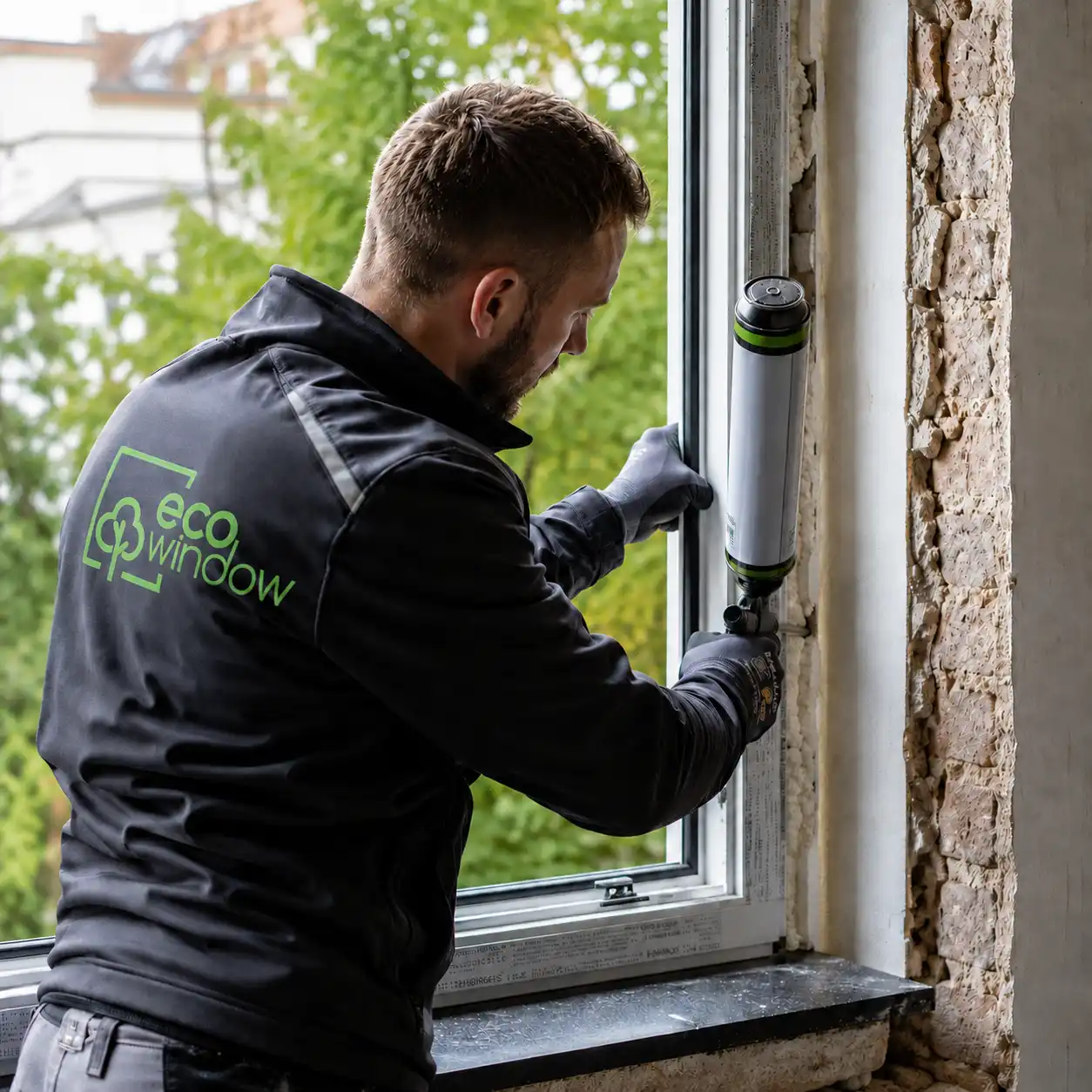 Monteur dichtet Fensterrahmen beim fachgerechten Einbau ab