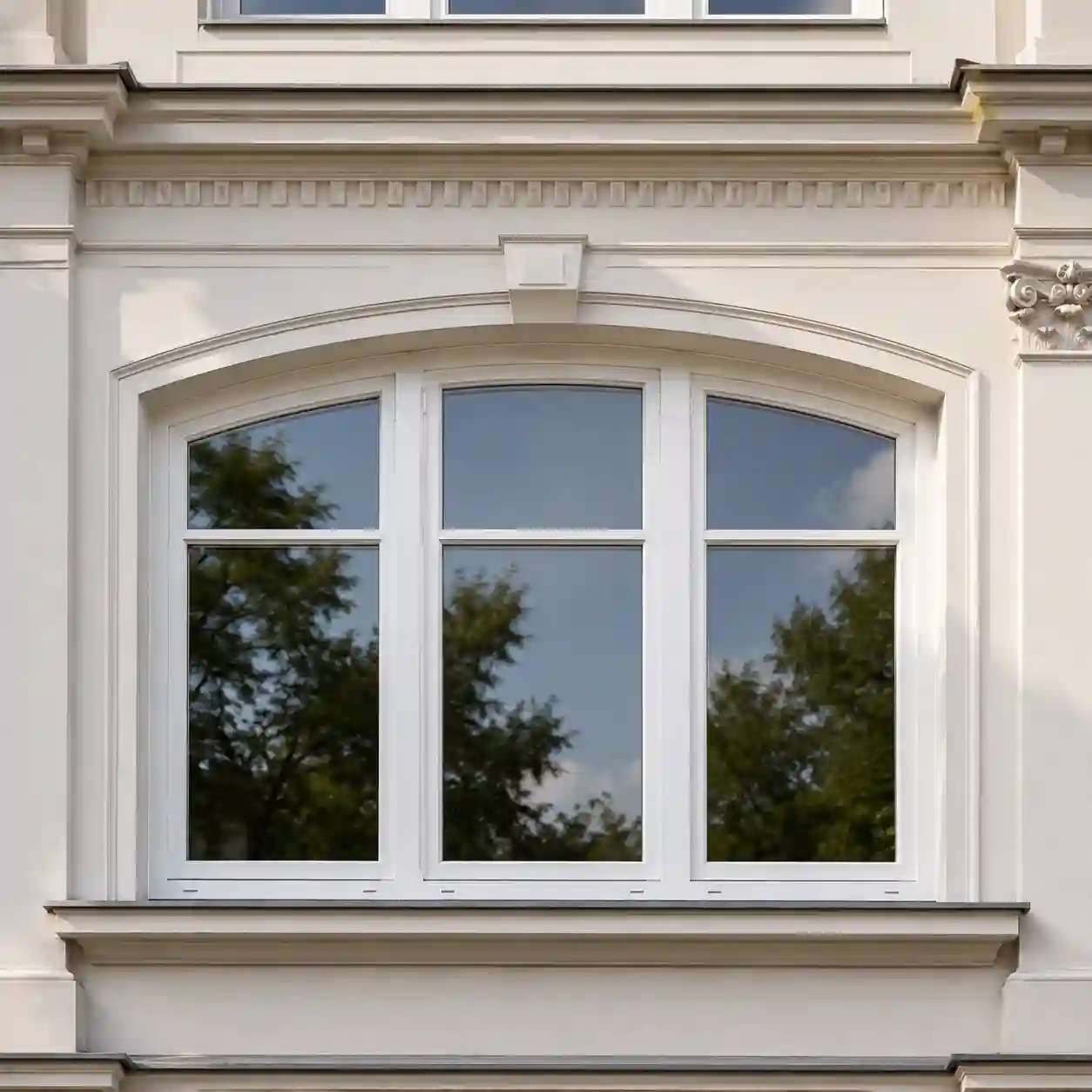 Weißes Stichbogenfenster aus Kunststoff in sanierter Altbau-Fassade von ecowindow