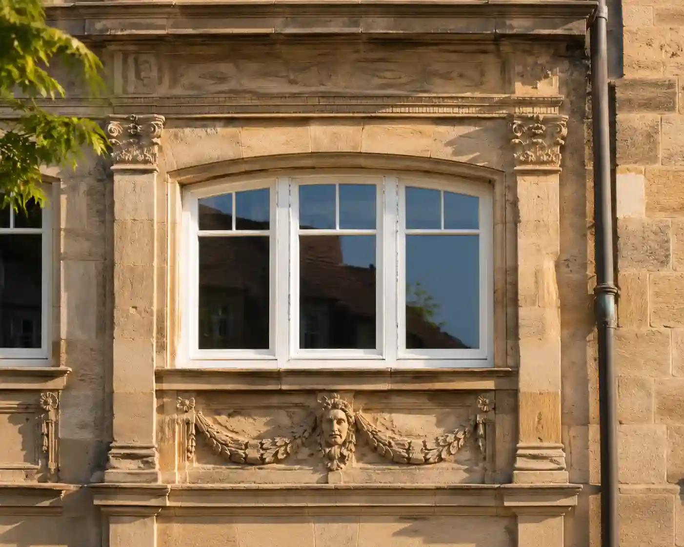 Weißes Stichbogenfenster mit Sprossen in sanierter historischer Renaissance-Fassade von ecowindow