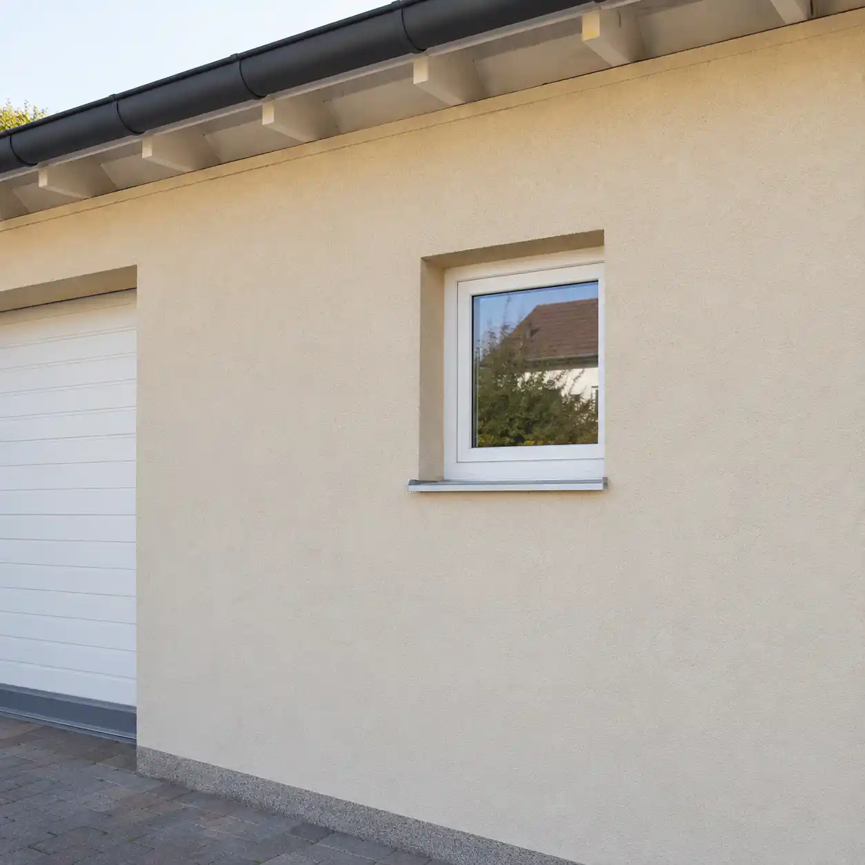Garagenfenster in Weiß an einer verputzten Garage, eingebaut von ecowindow