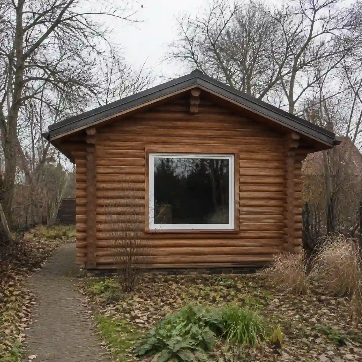 Massives Blockbohlenhaus im Winter mit beleuchtetem Fenster von ecowindow